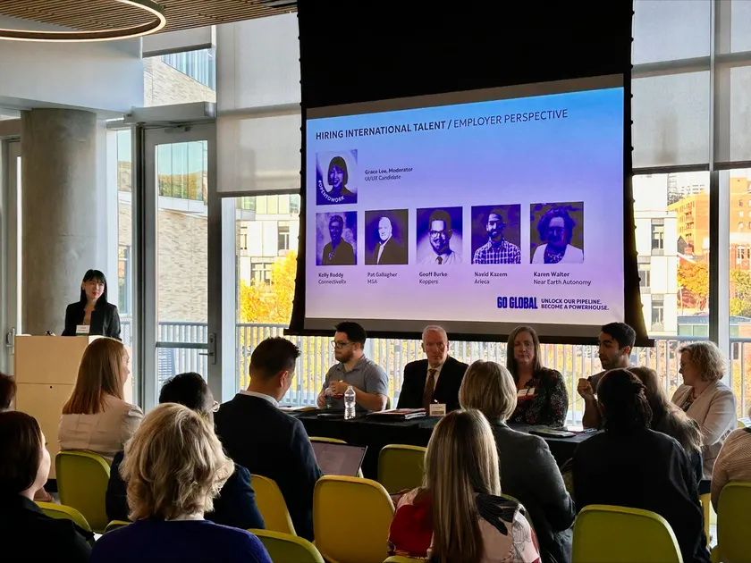 Grace moderating a panel on hiring international talent, with panelists seated at a table